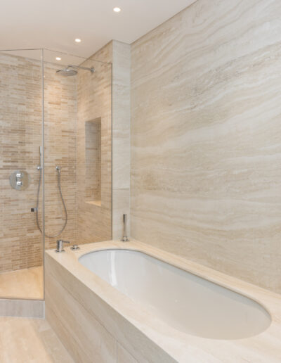 Built-in bathtub clad in Travertine Bianco with full height stone wall London
