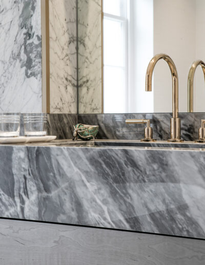 Detail of Bardiglio marble vanity top with brass tap in luxury London bathroom