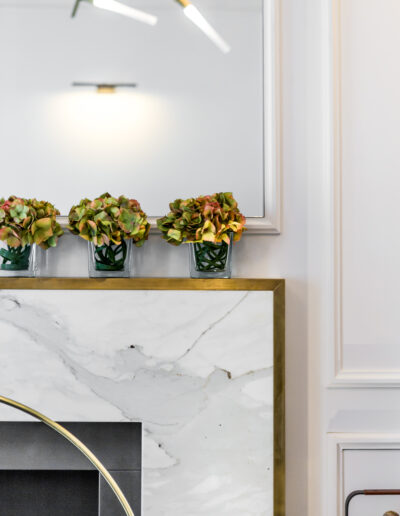 Detail of Calacatta marble fireplace surround with brass frame in luxury London residence
